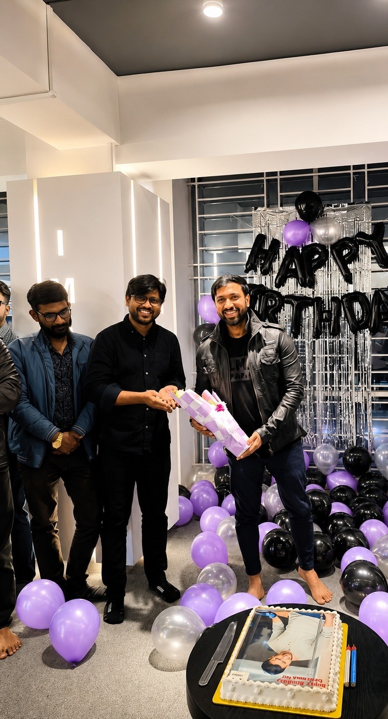 IMPIT team celebrating a colleague’s birthday with balloons, a gift, and a custom cake