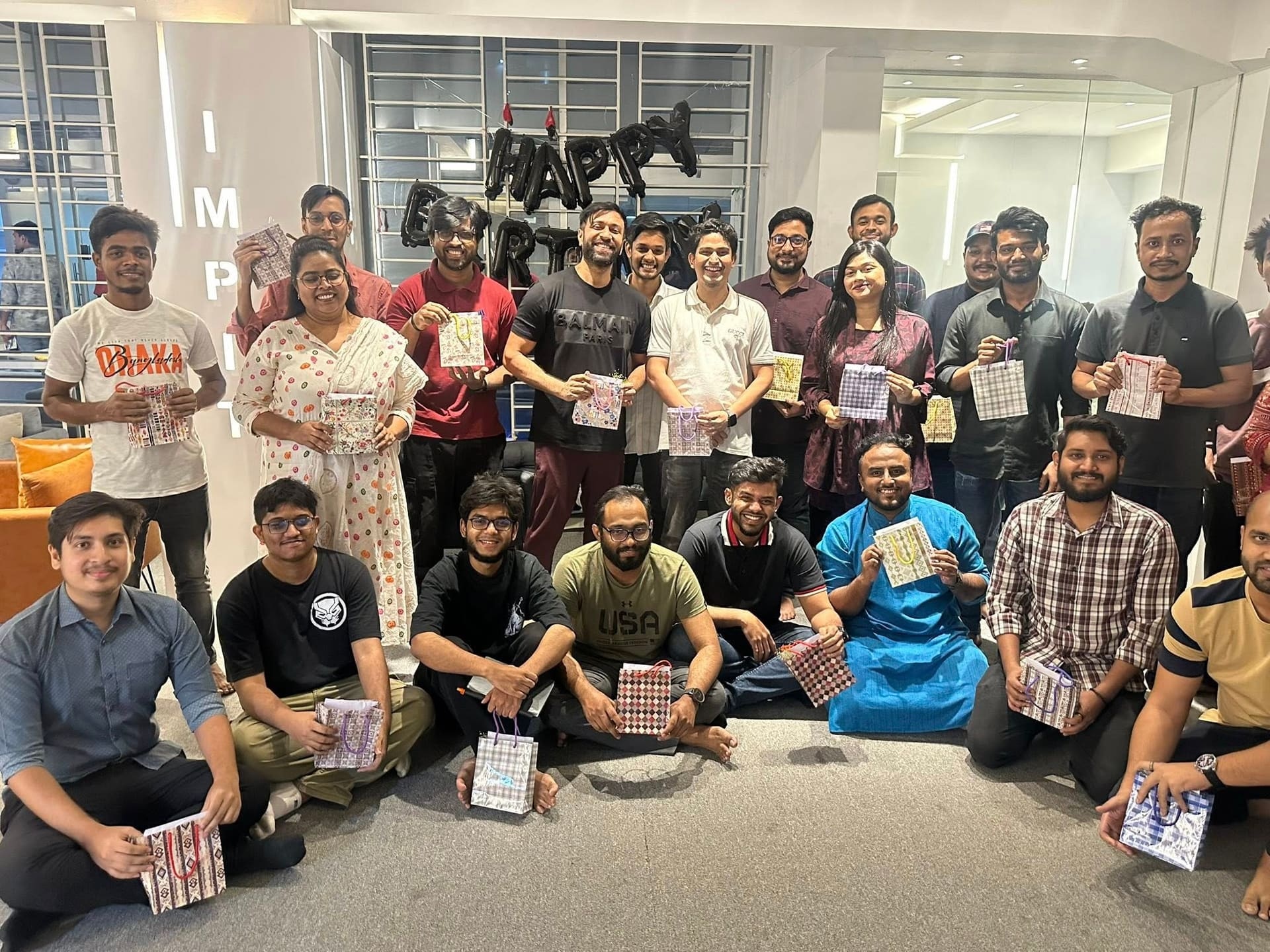IMPIT team members holding Eid ul-Fitr gift bags in the office