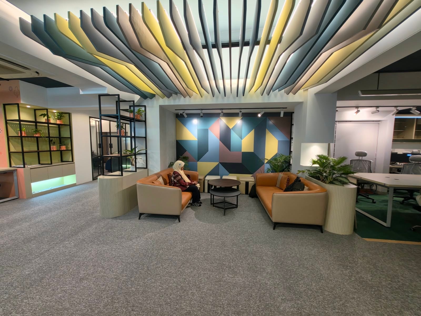 IMPIT lounge with a geometric feature wall and colorful ceiling